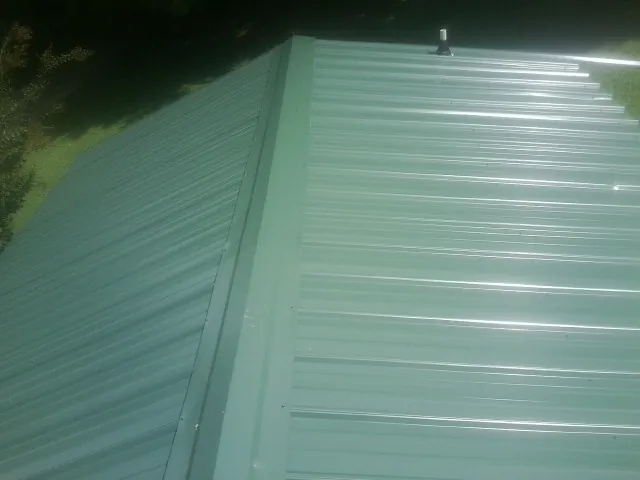New green metal panels meeting at the ridge of a roof — Flat Roof Repair work by our crew in Judith Gap