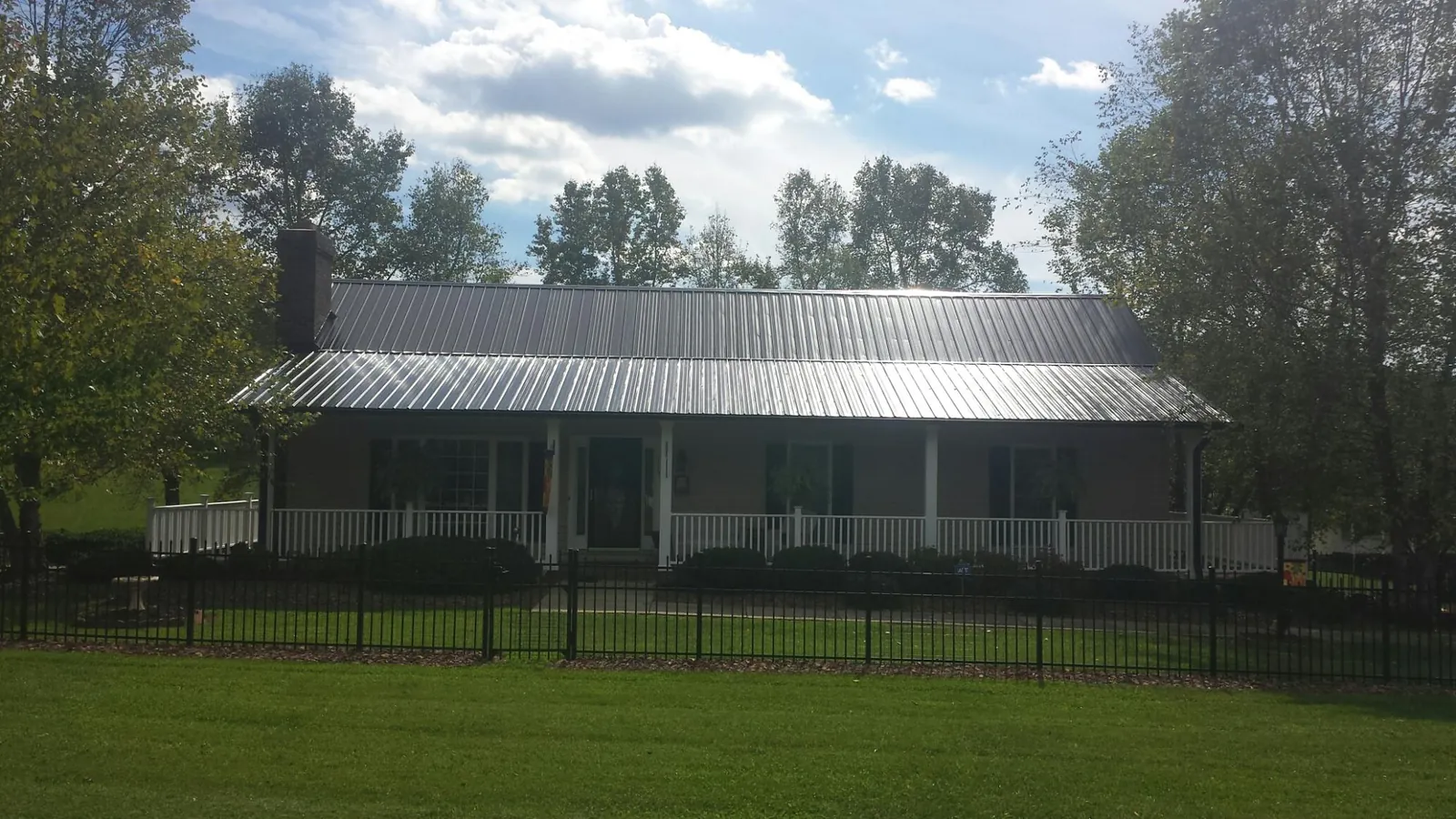 Gray metal roof on a brick ranch with a full width front porch — Gutter Guard Installation work by our crew in Judith Gap