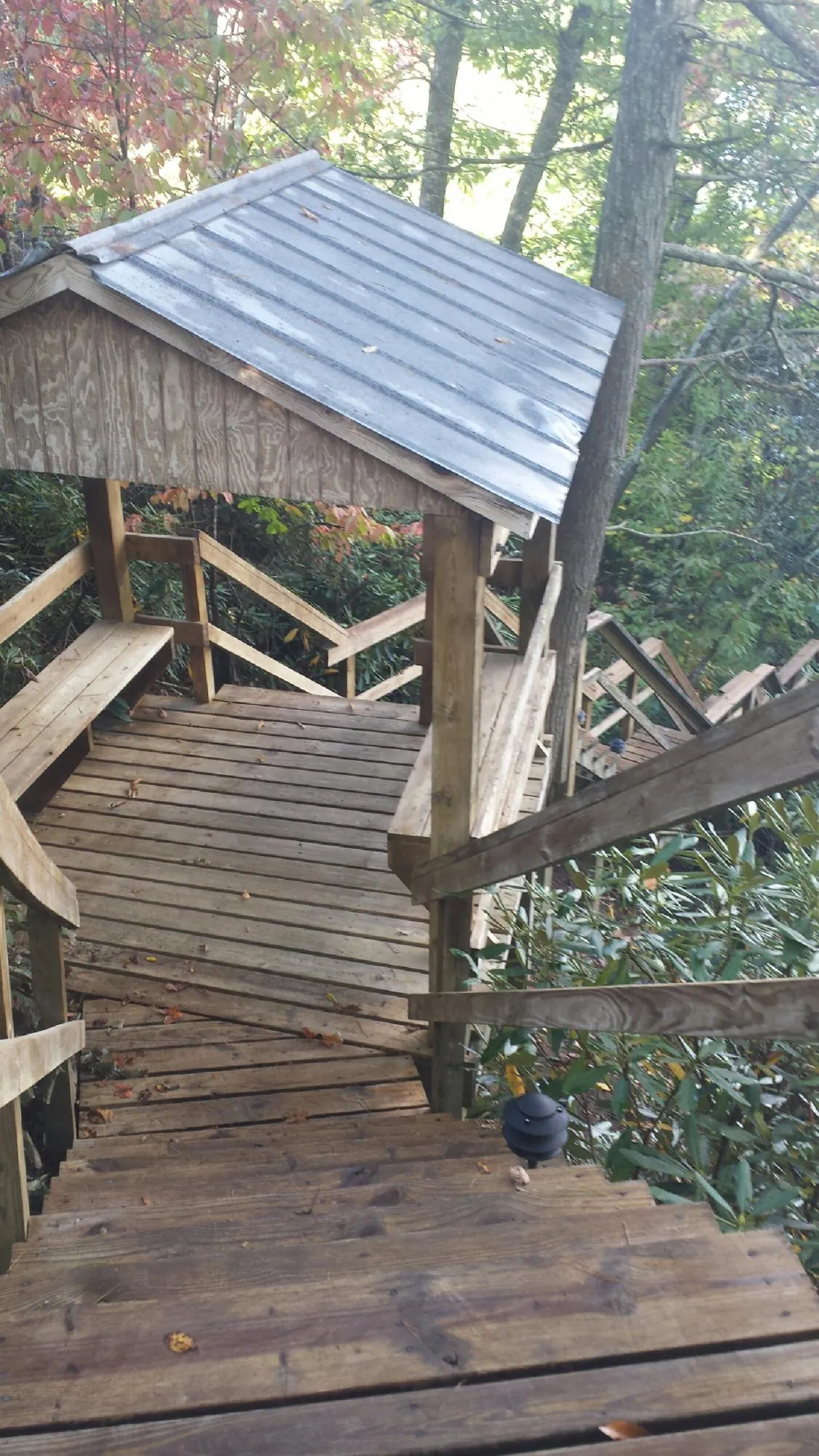 Metal roofed shelter over wooden steps on a wooded walkway — Skylight Repair & Installation work by our crew in Judith Gap