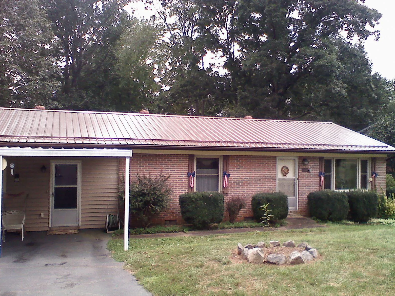 Bronze metal roof and carport on a brick ranch home — Roof Repair work by our crew in Judith Gap