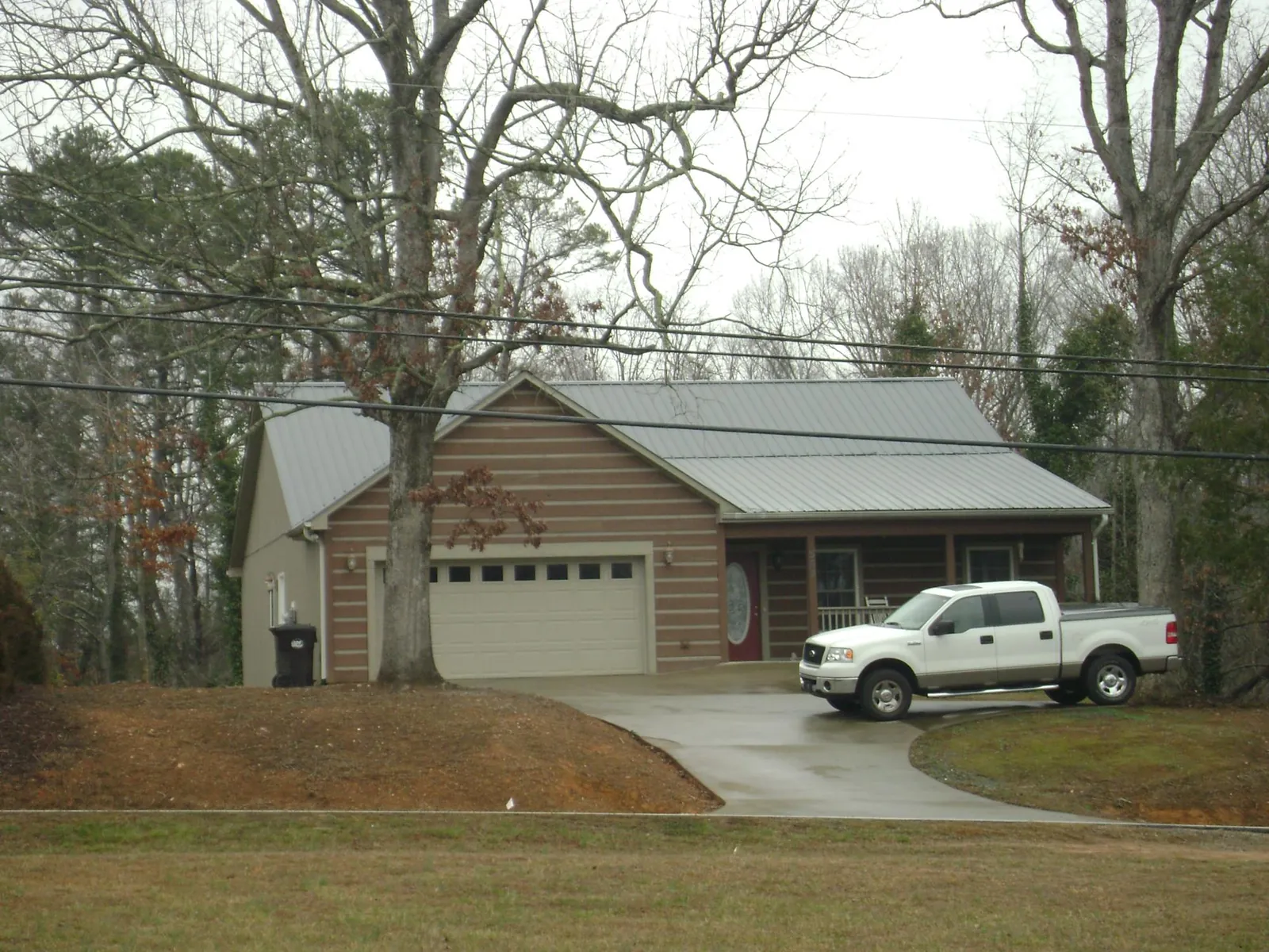 Gray metal roof on a log sided house with an attached two car garage in Judith Gap