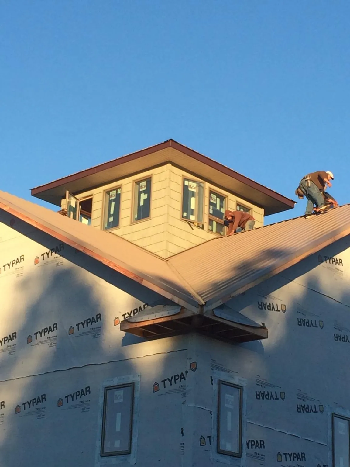 Roofers working around a rooftop cupola on a new metal roof at sunset — Roof Waterproofing in Judith Gap by Roofing Brothers